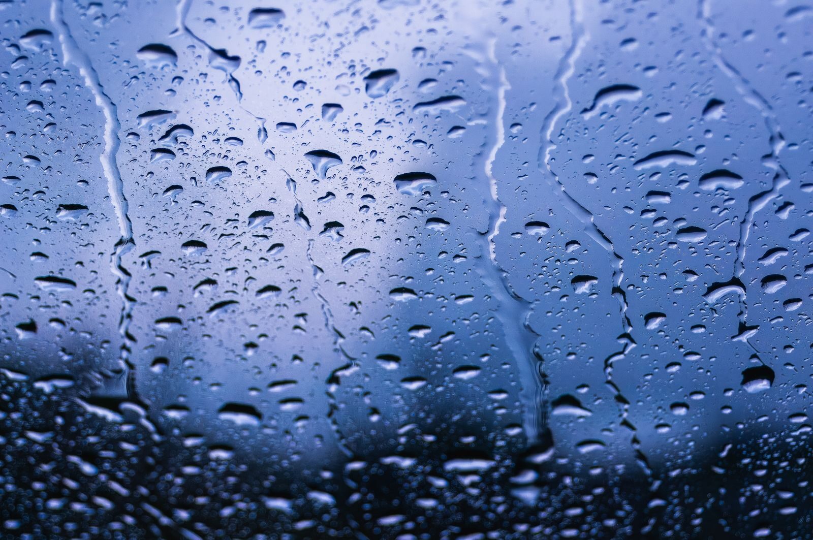 Condensation running down a cold window, where surface moisture stays high even when room air reads dry