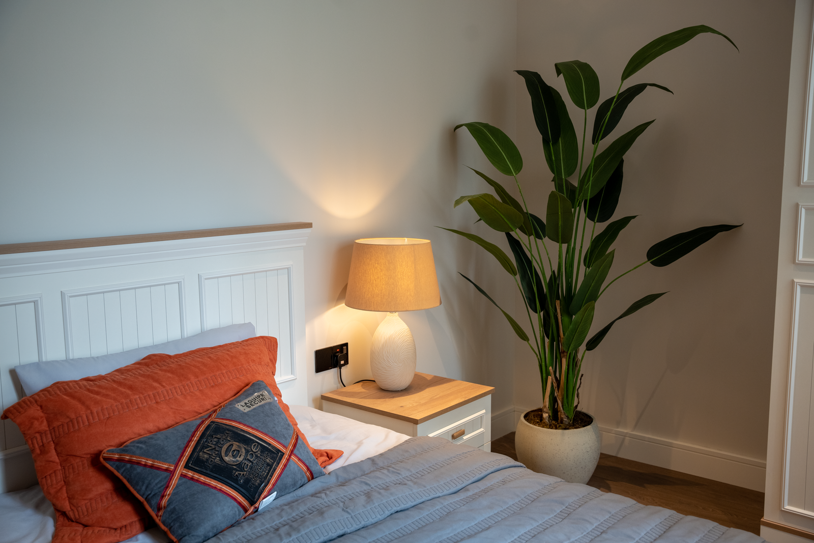A leafy houseplant beside a bed, the bedroom setup people wonder about when asking if plants are safe at night