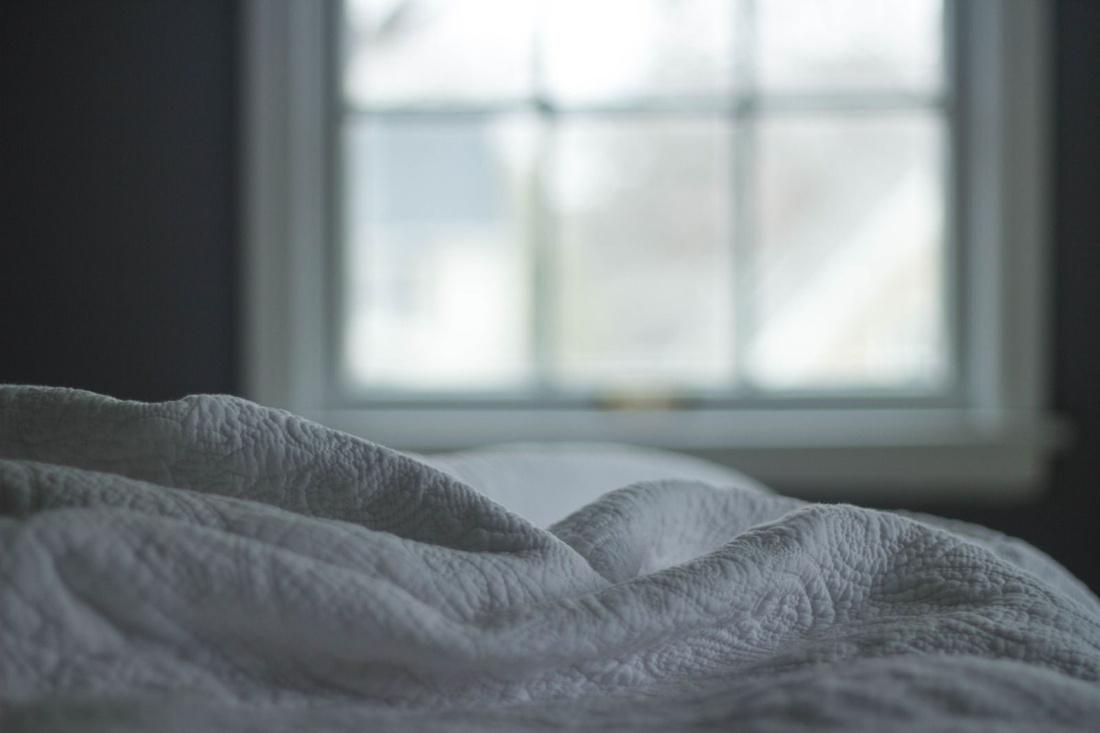 A bedroom bed by a window, the kind of room people worry about when they find mould in it