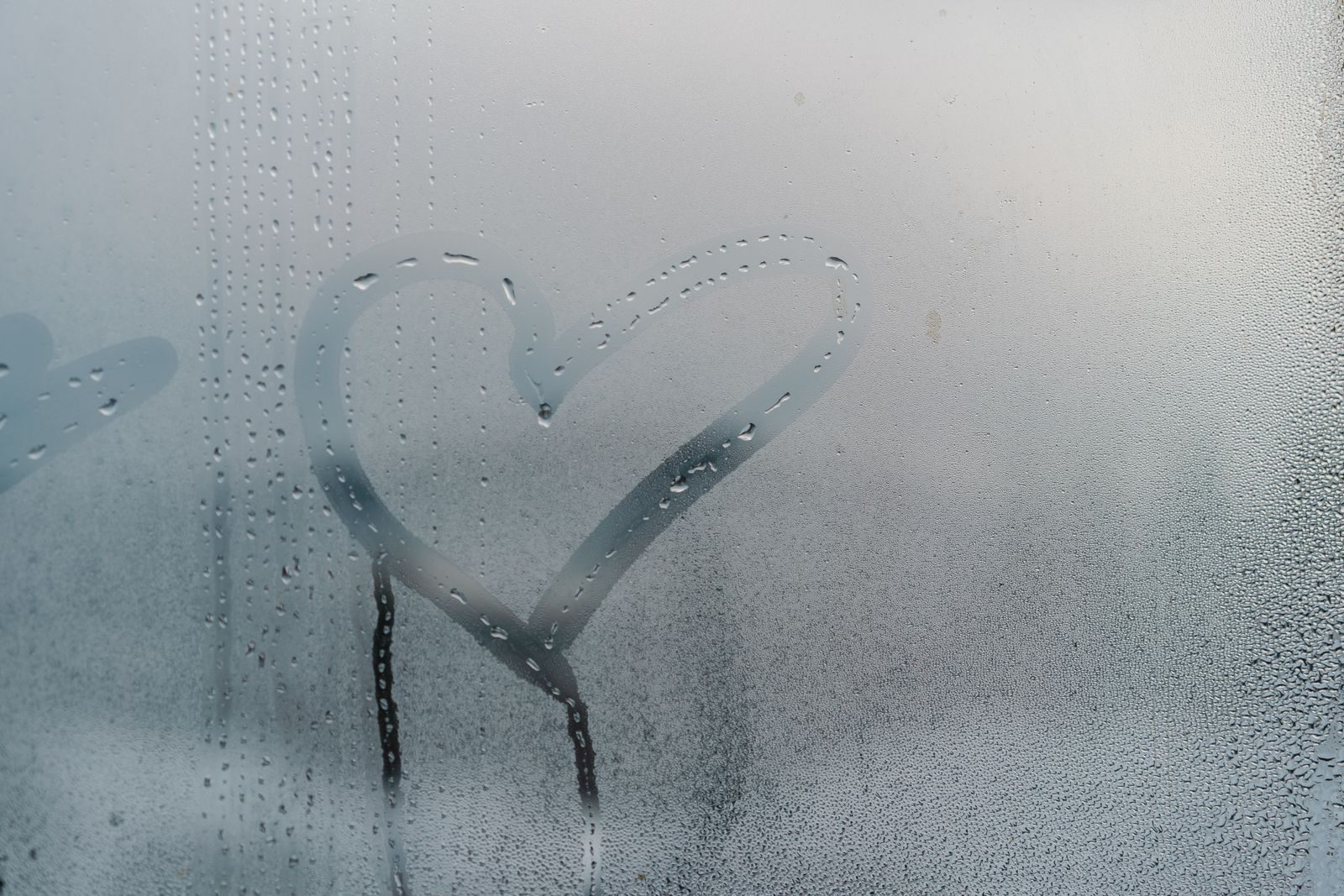 Heavy condensation on a misted winter window with a heart drawn in it, showing trapped indoor moisture