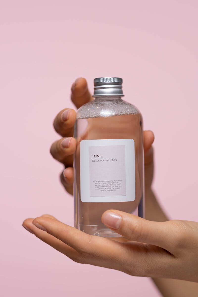 Hand holding a skincare tonic bottle showing INCI ingredient list on the label