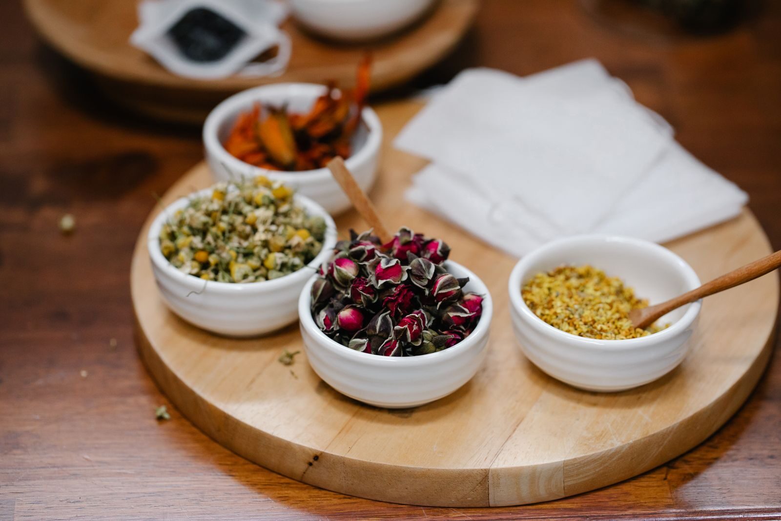 Bowls of dried botanical ingredients like flowers, seeds, and herbs used to make plant extracts