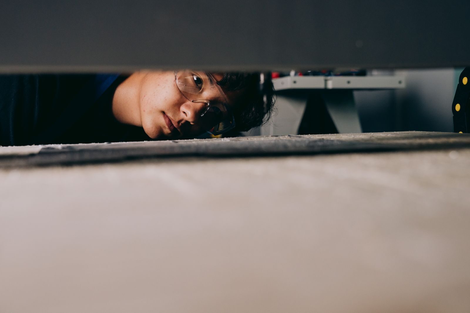 A person looking into a hidden gap under furniture while searching for the source of a mould smell