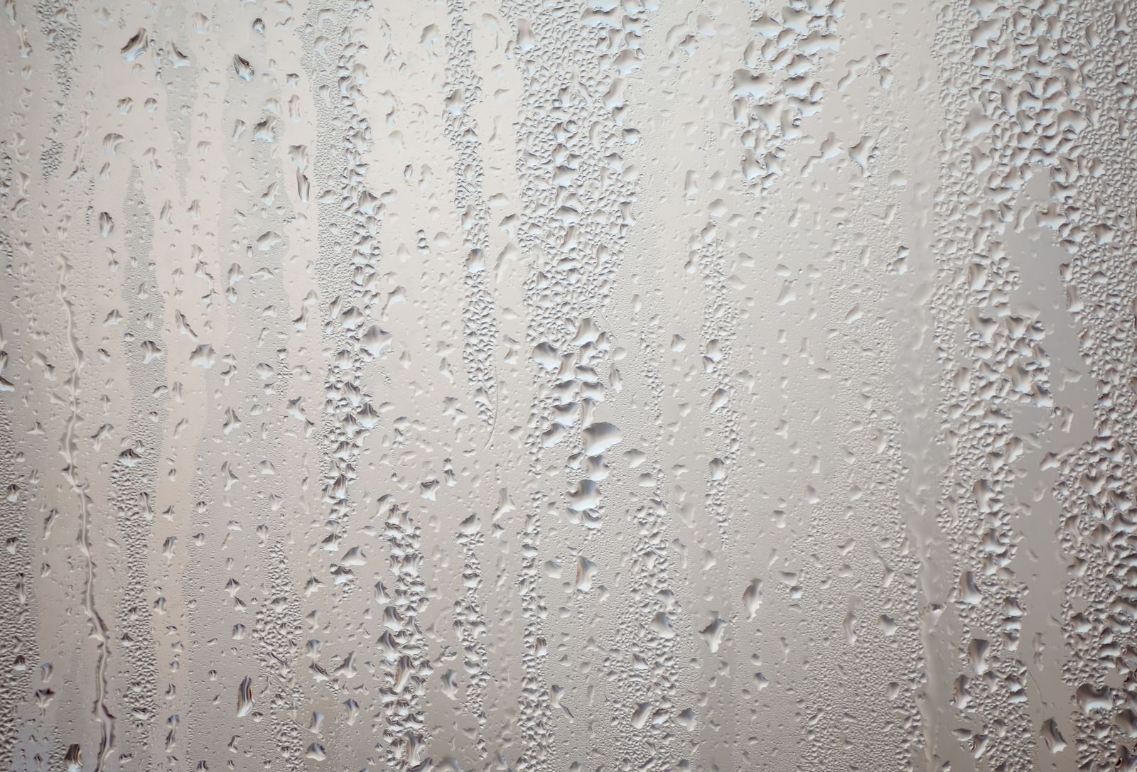 Condensation beaded and running down a misted bathroom window