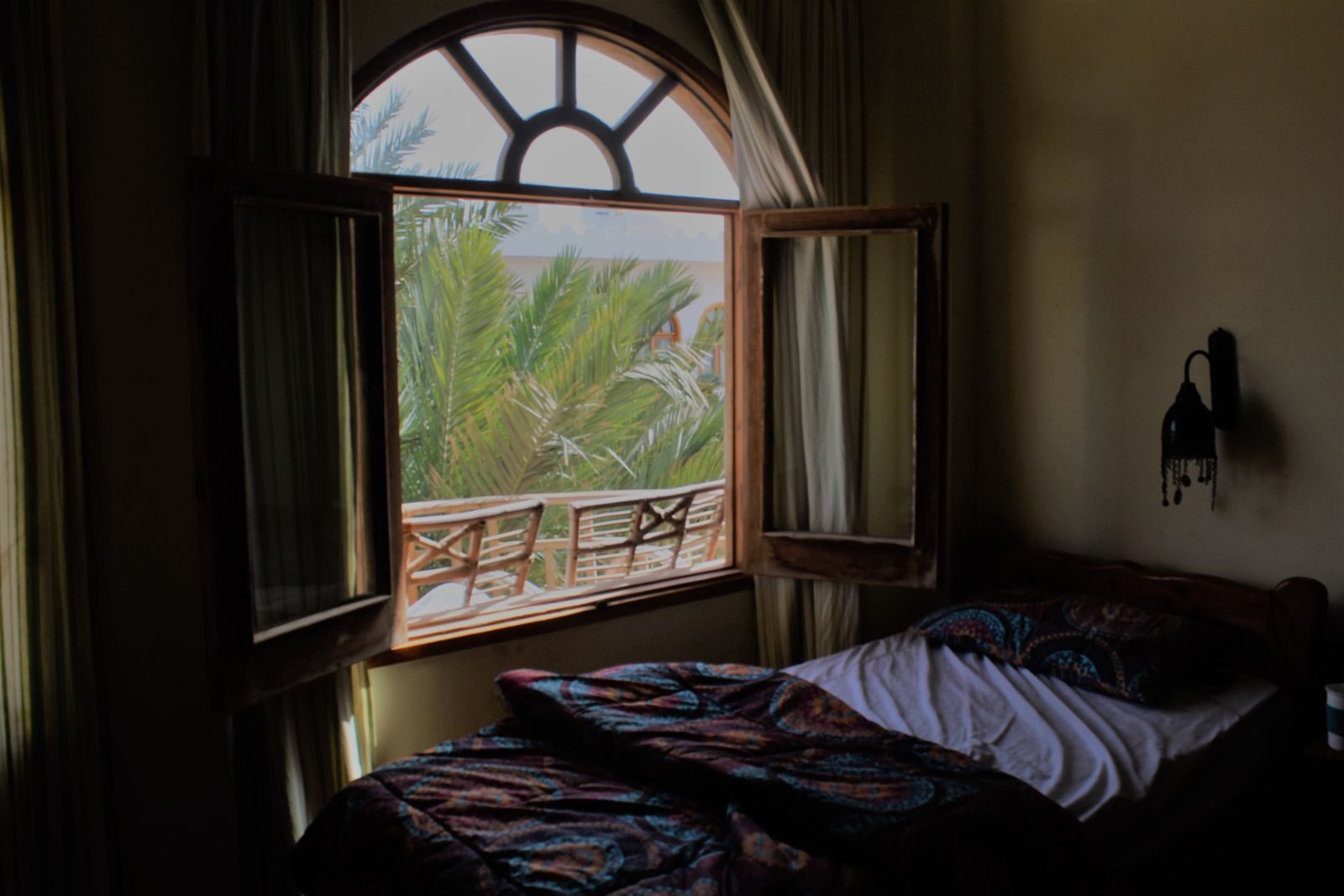 Open bedroom window at night with palm trees visible outside